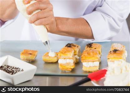 Chef decorating with a pastry bag with cream
