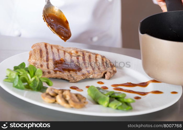 Chef finishing her plate and almost ready to serve at the table