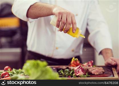Chef finishing steak meat plate with Finally dish dressing and almost ready to serve at the table. Chef finishing steak meat plate