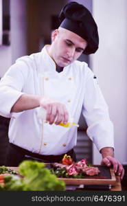 Chef finishing steak meat plate with Finally dish dressing and almost ready to serve at the table. Chef finishing steak meat plate