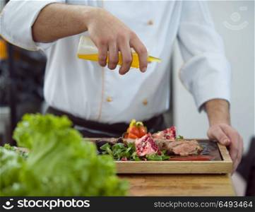 Chef finishing steak meat plate with Finally dish dressing and almost ready to serve at the table. Chef finishing steak meat plate