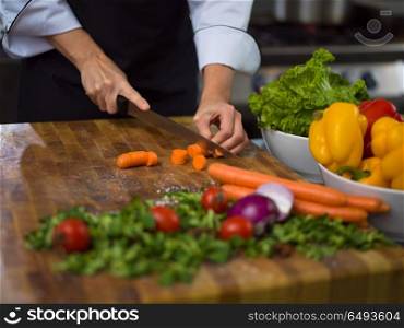 chef hands cutting carrots on a wooden table preparation for meal at restaurant. chef hands cutting carrots