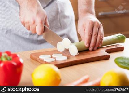 chef hands cutting leek in kitchen