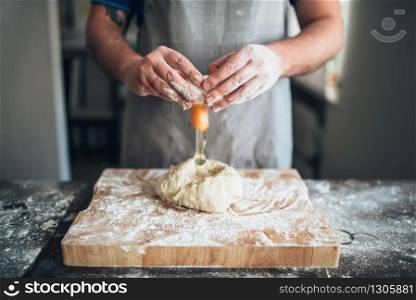 Chef hands mix the dough with egg. Bread preparation. Homemade bakery
