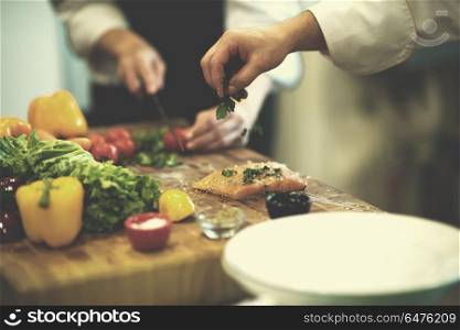 Chef hands preparing marinated Salmon fish fillet for frying in a restaurant kitchen. Chef hands preparing marinated Salmon fish