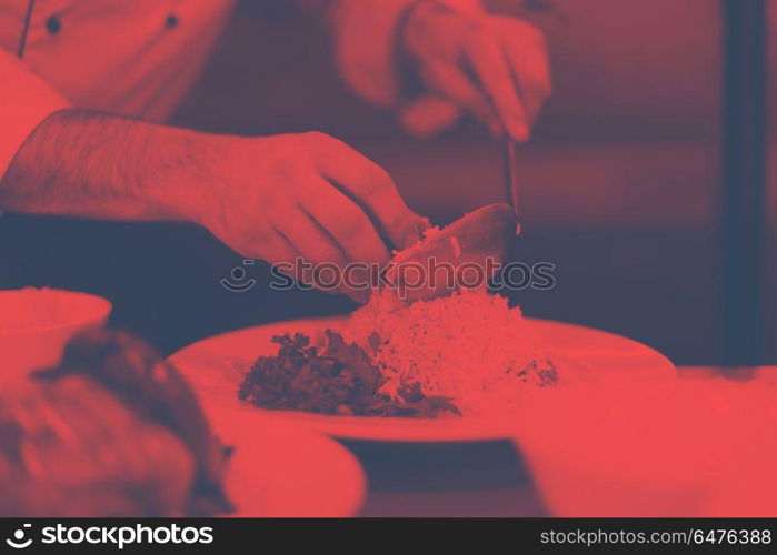 Chef hands serving vegetable risotto on restaurant kitchen. Chef hands serving vegetable risotto