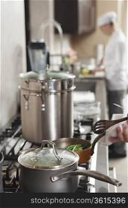 Chef heating saucepan on hob