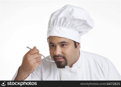 Chef holding a spoon to taste