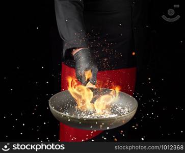 chef holds a round pan and throws the mixture of spices and white salt up, low key