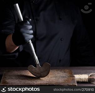 chef in black clothes holds in his hand a metal old knife for meat and vegetables