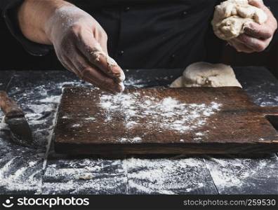 chef in black jacket, kneads dough made from white wheat flour, close up