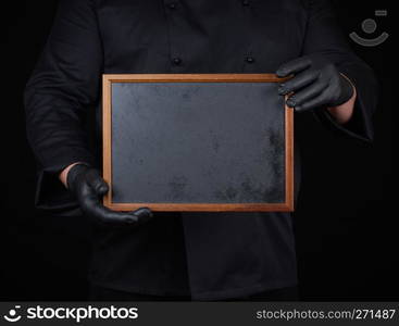 chef in black uniform and black latex gloves holds an empty wooden frame, copy space