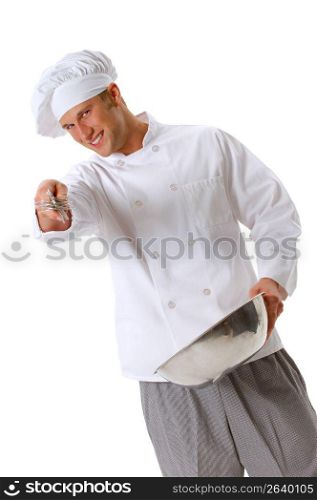Chef in chef?s whites and toque holding whisk and bowl mixing batter