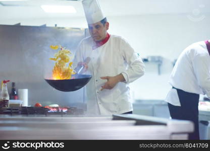 chef in hotel kitchen prepare vegetable food with fire