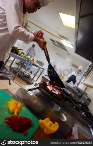 chef in hotel kitchen prepare vegetable food with fire