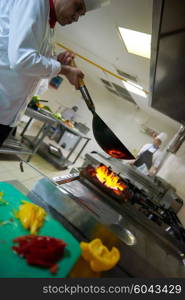 chef in hotel kitchen prepare vegetable food with fire