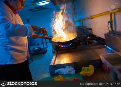 chef in hotel kitchen prepare vegetable food with fire