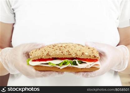 Chef in white dress holding a fresh sandwich in hands