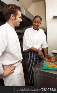 Chef Instructing Trainee In Restaurant Kitchen