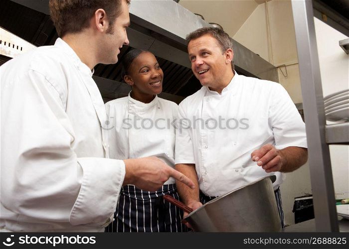 Chef Instructing Trainees In Restaurant Kitchen
