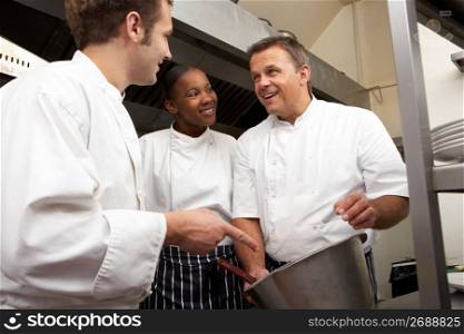 Chef Instructing Trainees In Restaurant Kitchen