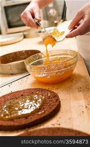 Chef pouring apricot jam to glass bowl making cake