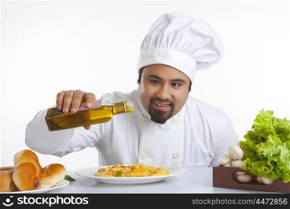 Chef pouring olive oil on pasta