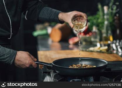 Chef pouring white wine into a frying pan with sliced shiitake mushrooms. Chef Pouring White Wine into Frying Pan with Sliced Shiitake Mushrooms