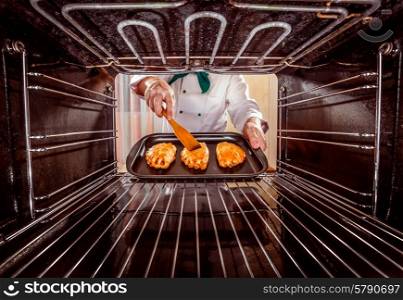 Chef prepares pastries in the oven, view from the inside of the oven. Cooking in the oven.
