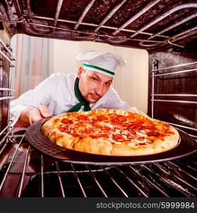 Chef prepares pepperoni pizza in the oven, view from the inside of the oven. Cooking in the oven.