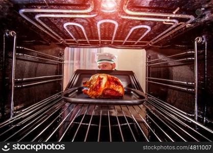 Chef prepares roast chicken in the oven, view from the inside of the oven. Cooking in the oven.