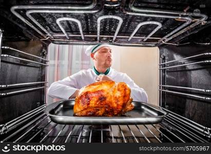Chef prepares roast chicken in the oven, view from the inside of the oven. Cooking in the oven.