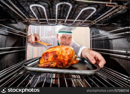 Chef prepares roast chicken in the oven, view from the inside of the oven. Cooking in the oven.