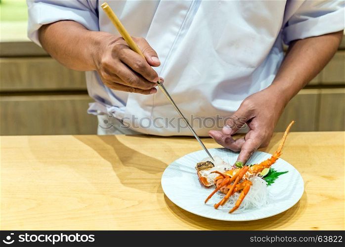 Chef preparing and cooking lobster sashimi