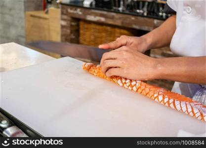 Chef preparing and cutting fresh salmon in Japanese restaurant