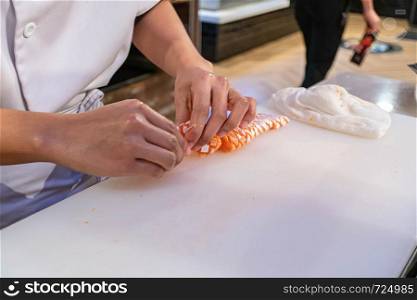 Chef preparing and cutting fresh salmon in Japanese restaurant