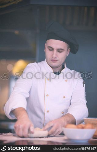 chef preparing dough for pizza on table sprinkled with flour. young chef preparing dough for pizza