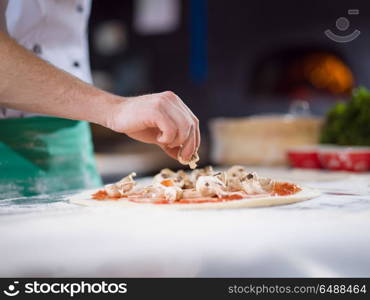 chef putting fresh mushrooms over pizza dough on kitchen table. chef putting fresh mushrooms on pizza dough