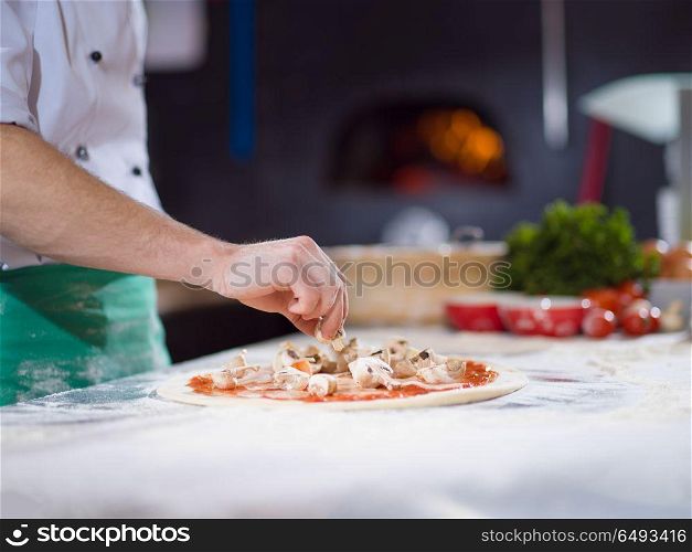 chef putting fresh mushrooms over pizza dough on kitchen table. chef putting fresh mushrooms on pizza dough