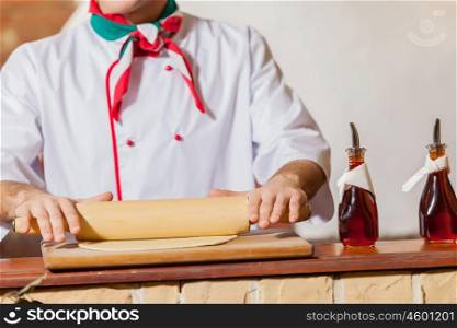 Chef rolling dough. Close-up image of cook hands rolling out dough