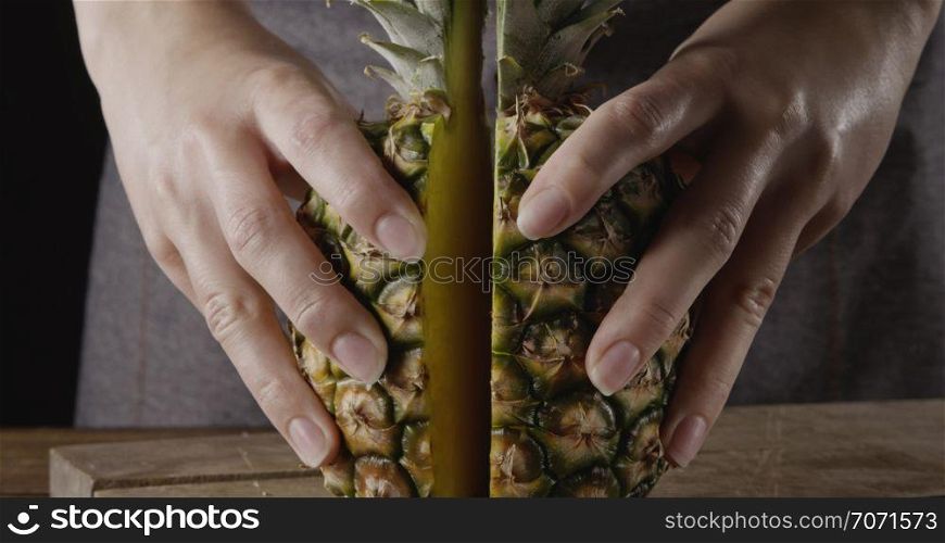 Chef&rsquo;s hands with fresh ripe natural organic exotic fruits cutting on a wooden table . Close up view. Concept of vegetarian diet eating.. Close up view. Woman&rsquo;s hands hold two pieces of juicy fresh natural organic pineapple on a wooden background.