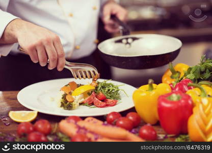 chef serving vegetable salad on plate in restaurant kitchen. chef serving vegetable salad