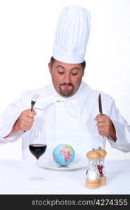 chef sitting at table looking at globe in dish