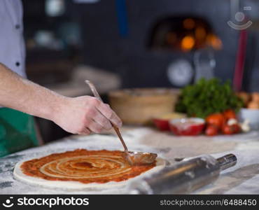 Chef smearing pizza dough with ketchup