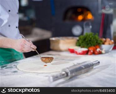 Chef smearing pizza dough with ketchup