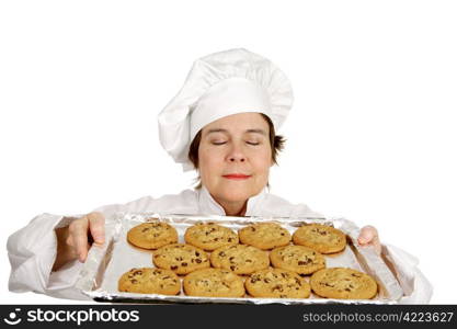 Chef smelling the aroma of a freshly baked batch of chocolate chip cookies. Isolated on white.
