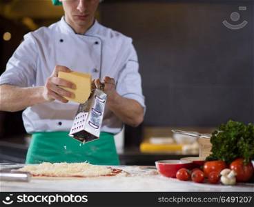 chef sprinkling cheese over fresh pizza dough on kitchen table. chef sprinkling cheese over fresh pizza dough
