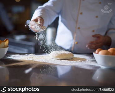 chef sprinkling flour over fresh pizza dough on kitchen table. chef sprinkling flour over fresh pizza dough