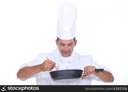 Chef stirring contents of saucepan