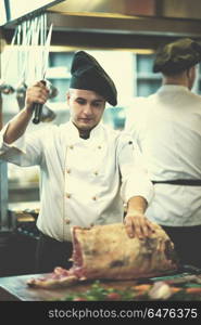 chef using ax while cutting big piece of beef on wooden board in restaurant kitchen. chef cutting big piece of beef